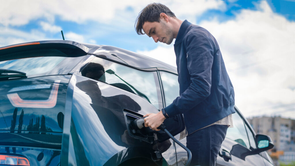 Man charging his electric car at charge station Ref: Image by frimufilms on Freepik